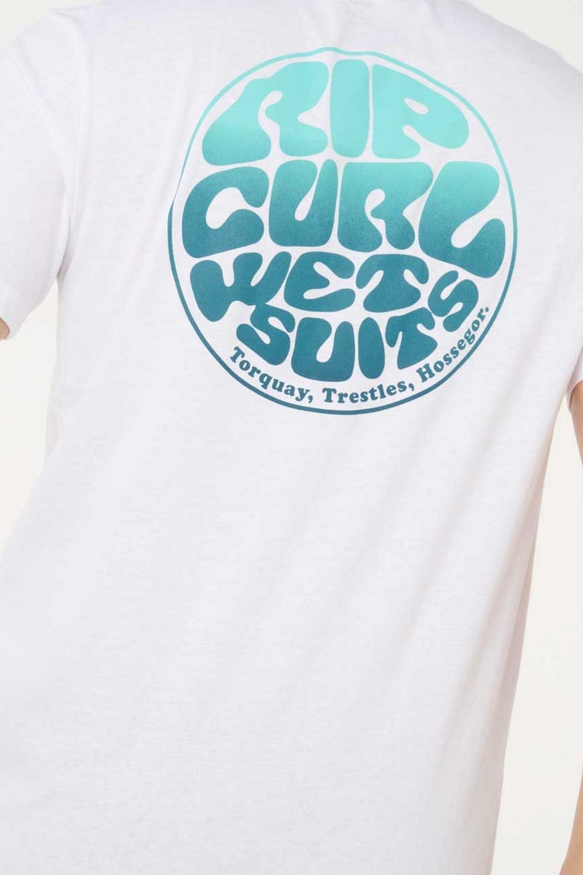Back of a white Rip Curl Wettie Passage Icon Tee showing a round blue-green "RIP CURL WETSUITS" logo and "Torquay, Trestles, Hossegor" below. Made from soft knit fabric in a comfortable standard fit.