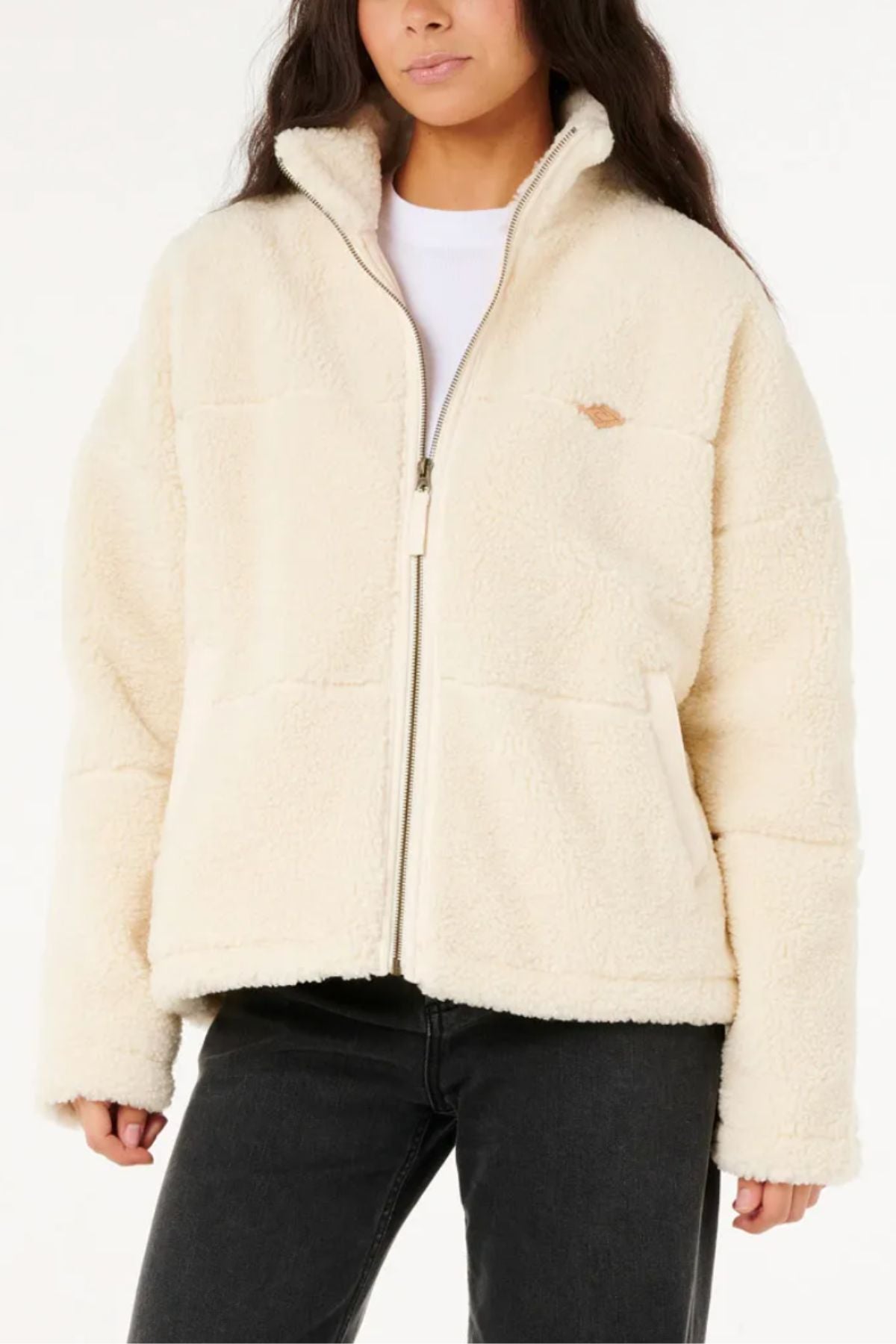 A woman models the Rip Curl Cala Nights Sherpa Jacket, made from recycled polyester sherpa, layered over a white shirt and black jeans against a plain white background—an ideal addition to any winter wardrobe.