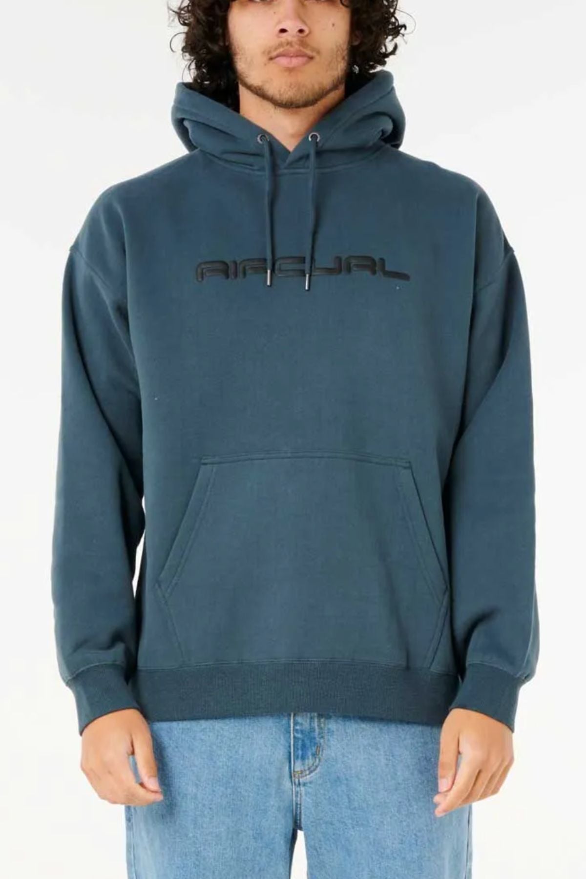 A person stands against a white background wearing the Rip Curl Dosed Up Hood in teal, featuring black chest text and crafted from cotton polyester fleece, paired with light blue jeans.