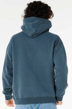 A person with curly hair is seen from behind, wearing a blue Rip Curl Dosed Up Hood made from responsibly sourced materials and light blue jeans, set against a plain white background.