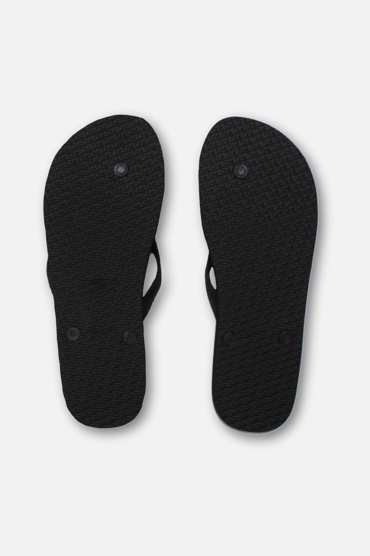A pair of black Rip Curl Brand Logo Bloom Thongs, shown from the bottom against a white background, features textured soles, two circular plugs per sandal, and an ergonomic moulded design.