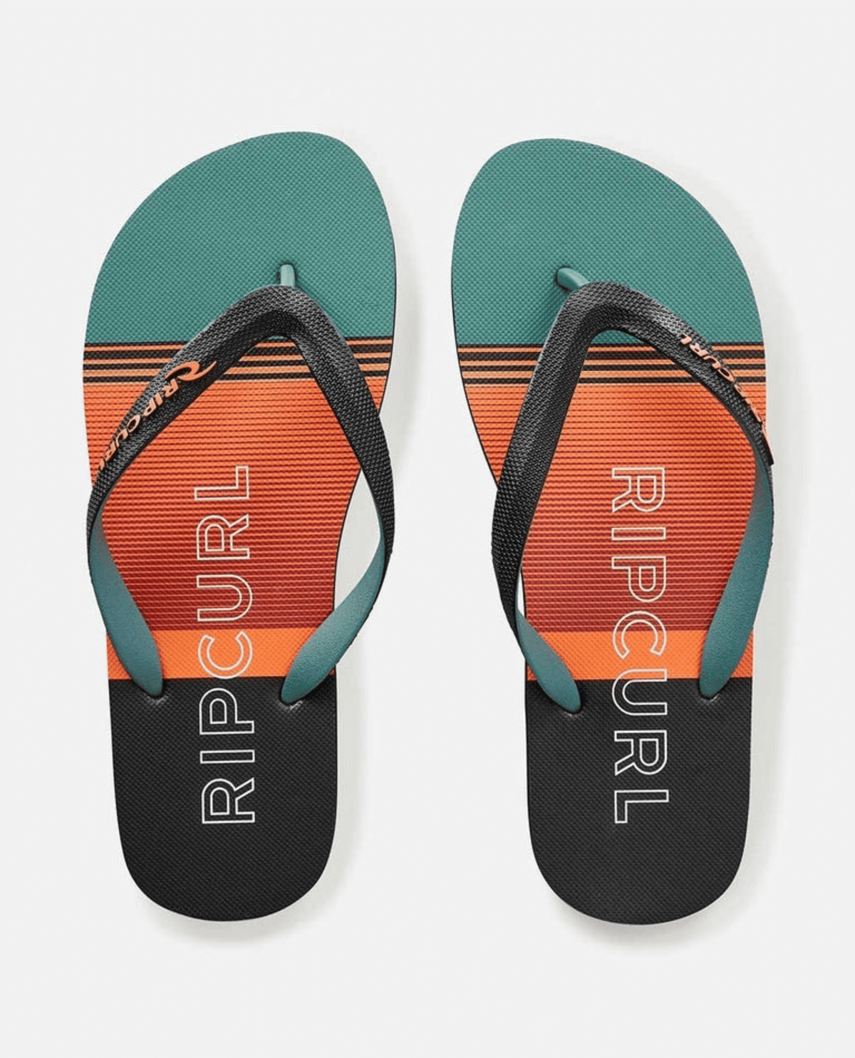 The Rip Curl Breakers Bloom Thongs have black straps and gradient teal, orange, and black striped soles with "RIP CURL" in white. Made with BLOOM algae-blended foam, they embody eco-friendly fashion against a plain white backdrop.