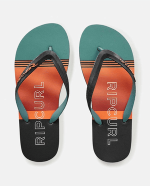 The Rip Curl Breakers Bloom Thongs have black straps and gradient teal, orange, and black striped soles with "RIP CURL" in white. Made with BLOOM algae-blended foam, they embody eco-friendly fashion against a plain white backdrop.