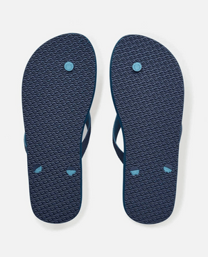 The image displays the soles of blue Rip Curl Breakers Bloom Thongs, showcasing textured patterns with three circular impressions each. Made from eco-friendly BLOOM algae-blended foam, these fashion staples are positioned side by side on a light gray background.