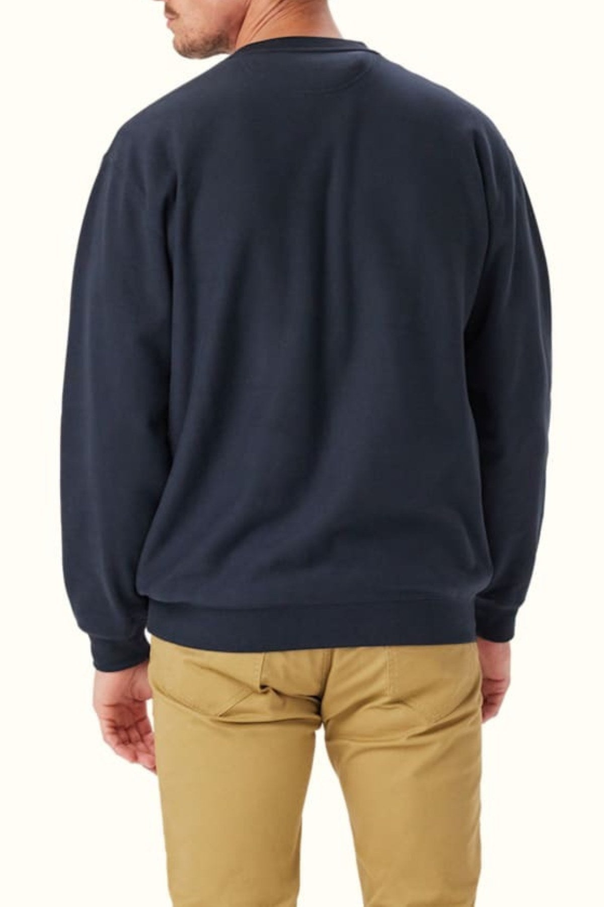 A man is seen from behind wearing a relaxed-fit RM Williams Bale Loopback Sweatshirt in dark navy and light khaki pants, standing against a plain off-white background.