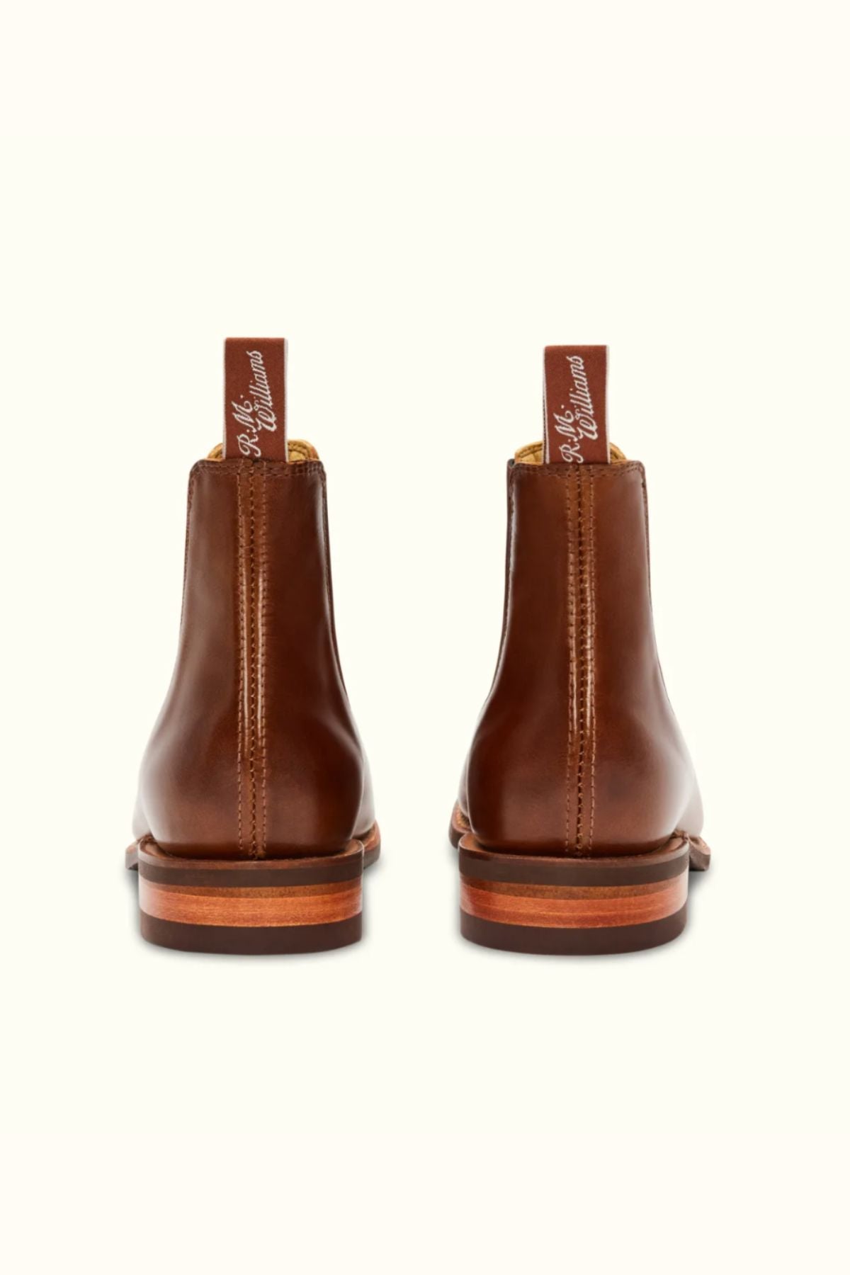 The RM Williams Comfort Craftsman Boot in brown pull-up leather, shown from the back with signature pull tabs featuring white script and contrasting rubber soles, is set against a plain light background.