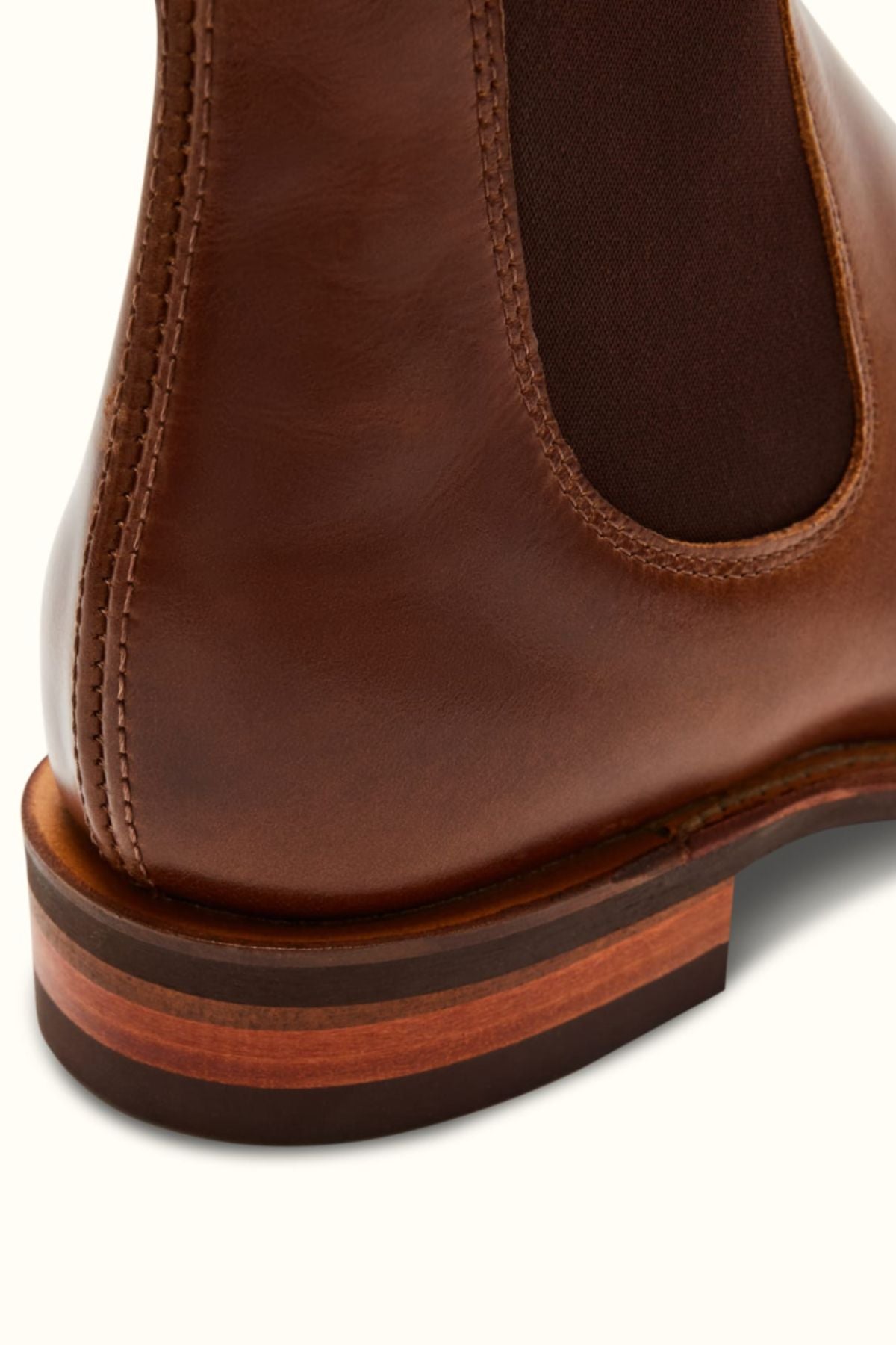 Close-up of the heel and side of the RM Williams Comfort Craftsman Boot in brown pull-up leather, highlighting detailed stitching, elastic side panel, a stylish wooden stacked heel, and durable rubber sole.