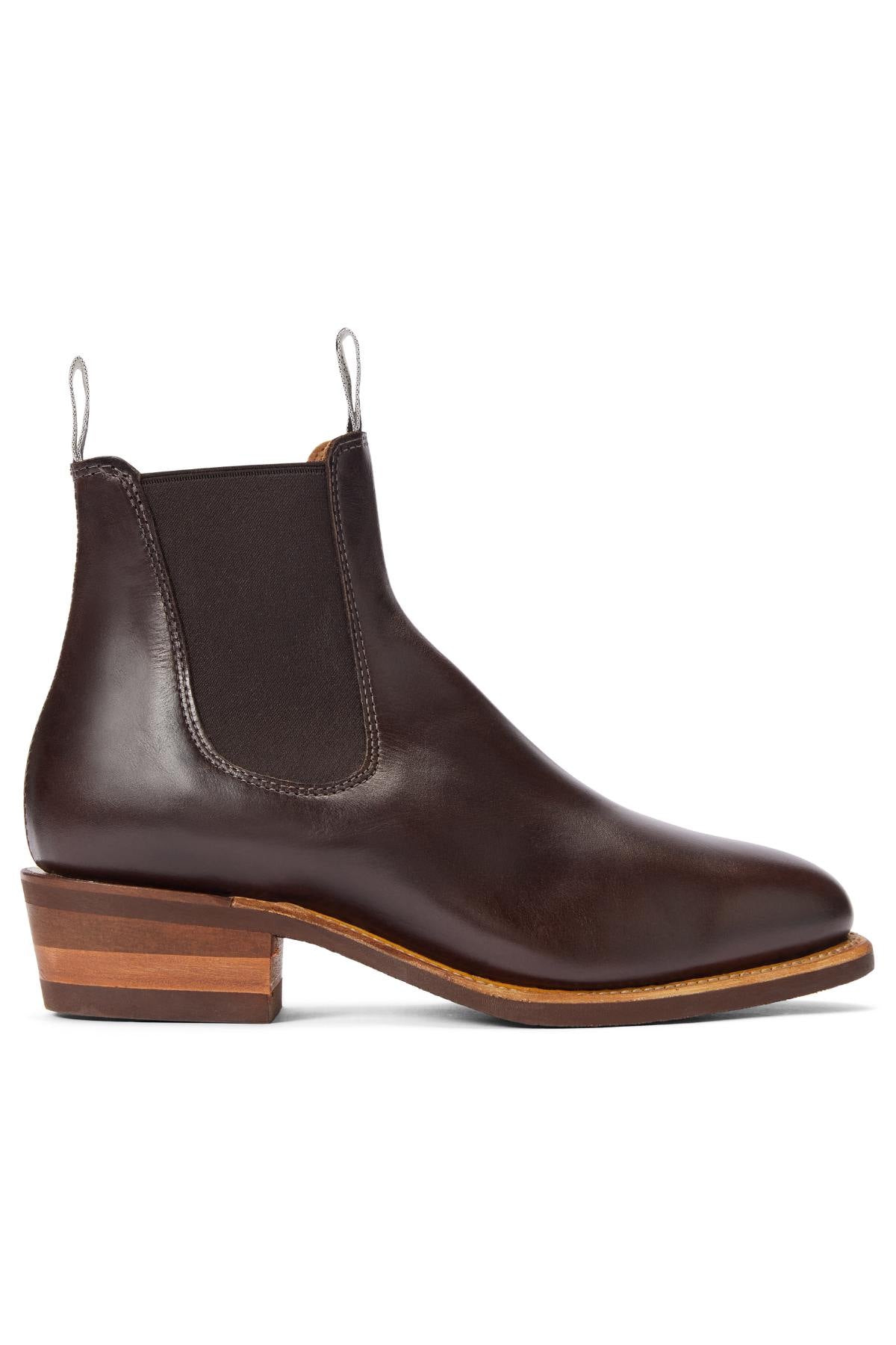 The RM Williams Comfort Lady Yearling Rubber Sole Boot is a dark brown Chelsea boot in pull-up leather with elastic side panels, pull tabs, and a stacked wooden heel, shown in side profile on a white background.