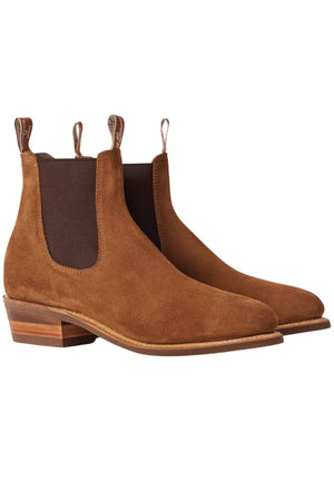 The RM Williams Comfort Suede Lady Yearling Rubber Sole Boot features brown Italian suede, dark elastic panels, pull tabs, low stacked heels, and rounded toes. Inspired by timeless RM Williams style, shown against a white background.