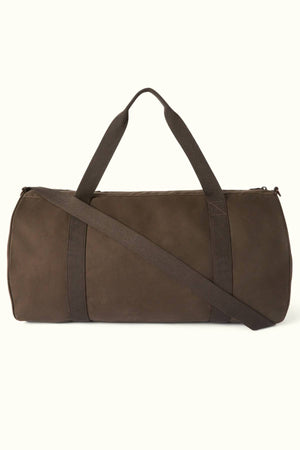 The RM Williams Ditty Bag is a brown waxed cotton canvas duffel with two short handles and an adjustable shoulder strap, perfect for travel, shown against a plain light background.