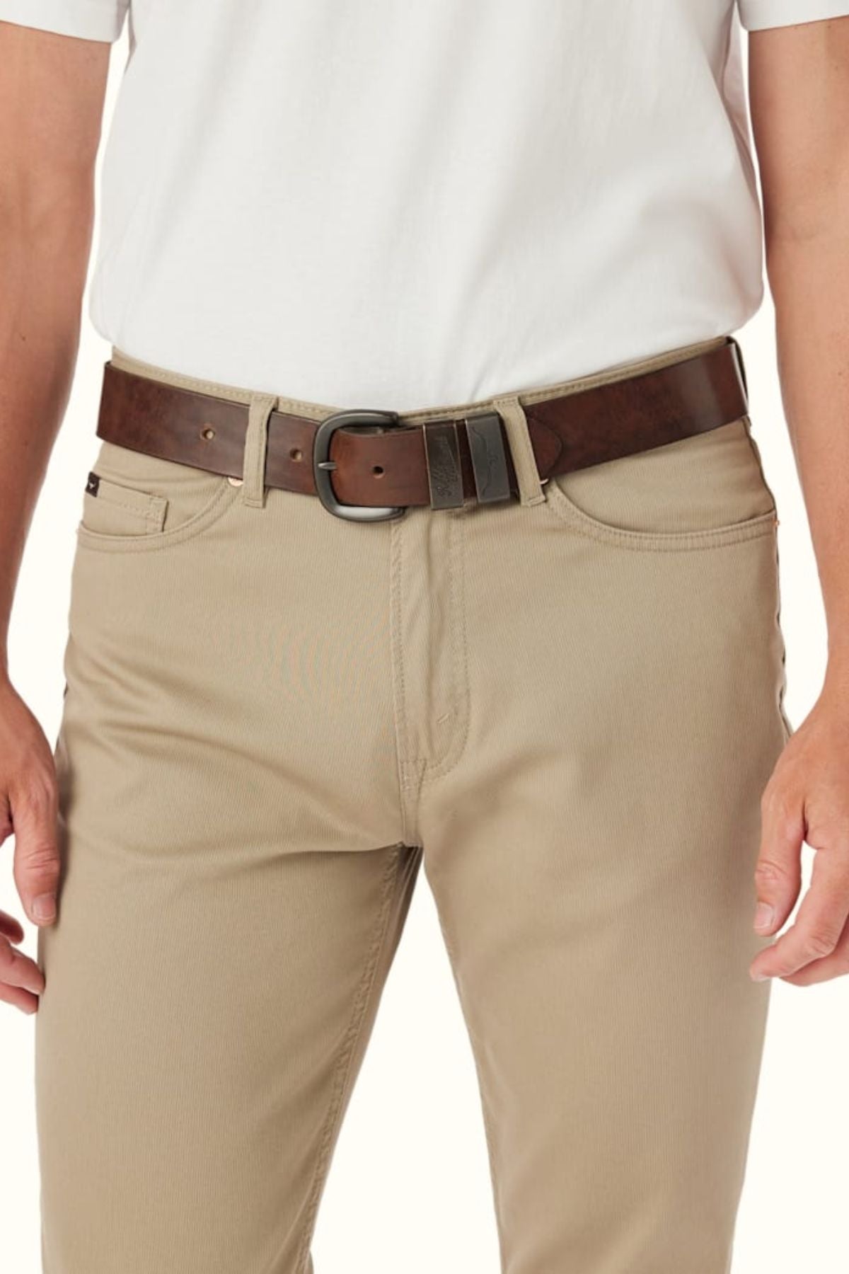 A person wearing a white shirt, beige pants, and the RM Williams Drover Belt—dark brown leather with double keepers and a silver buckle. The image is cropped to show only the waist and upper legs.