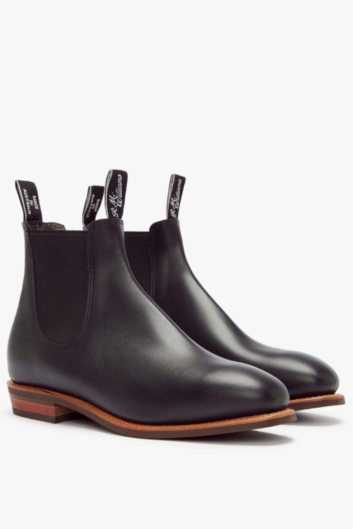 The RM Williams Erica Boot, featuring black full-grain leather, elastic side panels, pull tabs, and brown wooden soles, showcases signature Craftsman Boot quality against a white background.