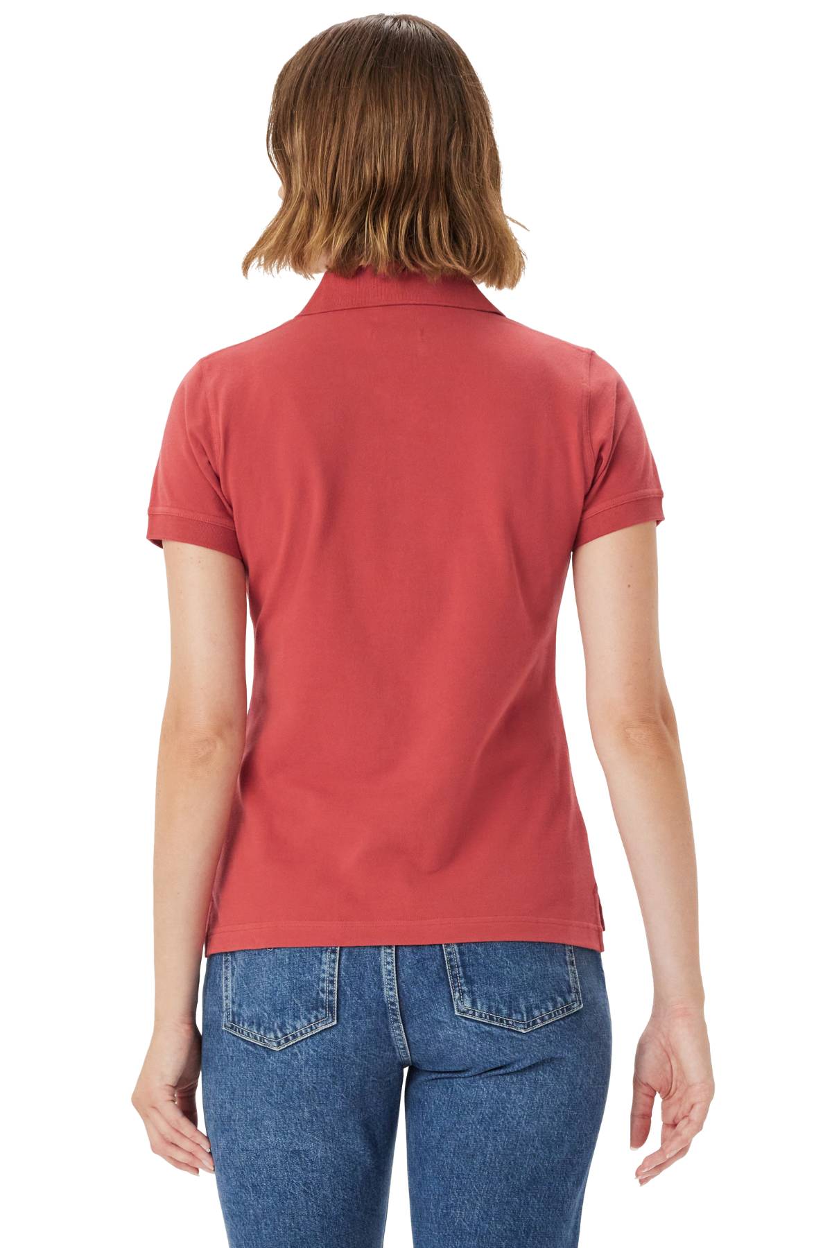 A person with short brown hair wearing the RM Williams Margaret Polo in red with longhorn embroidery and blue jeans stands with their back to the camera against a white background.