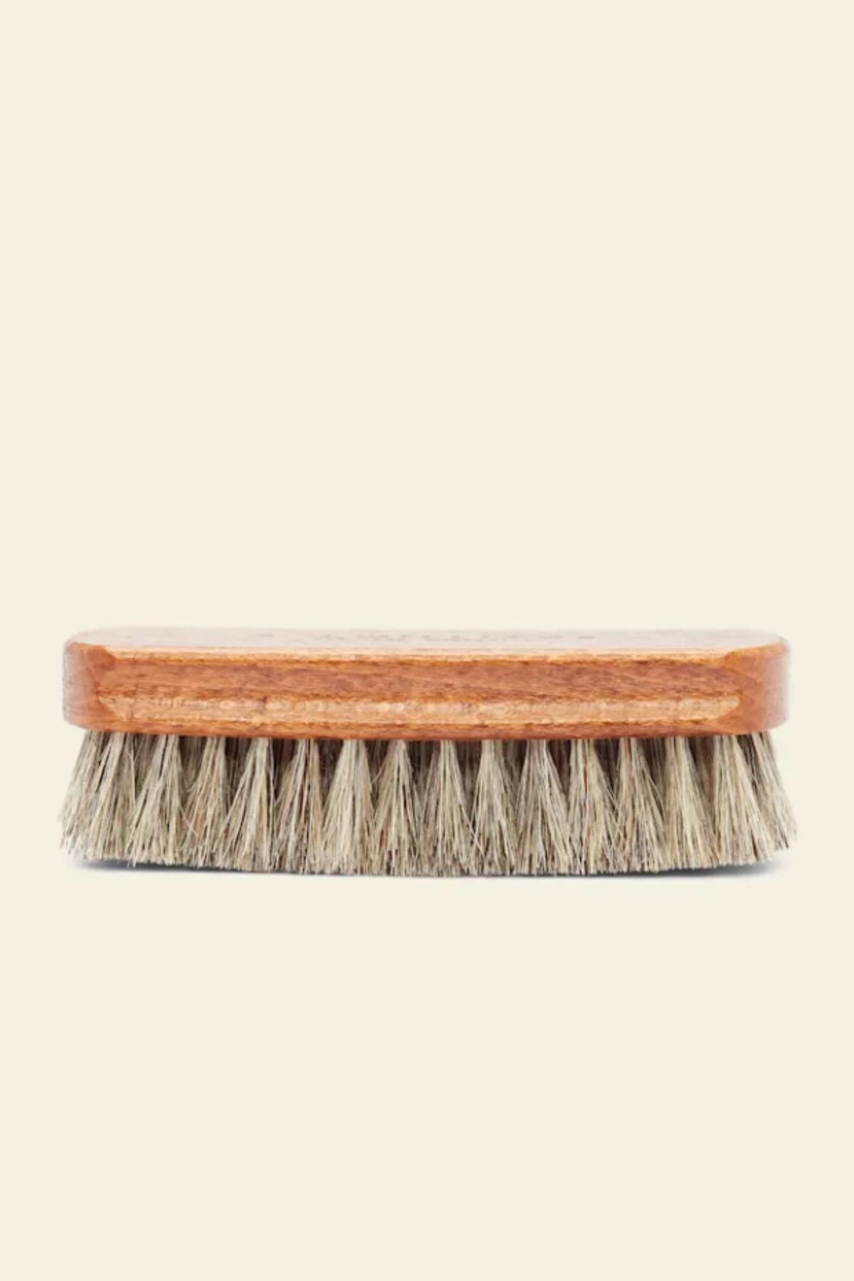 The RM Williams Medium Brush, featuring dense light brown horse hair bristles and a wooden body, is displayed against a plain light background.