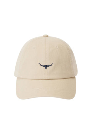 The RM Williams Mini Longhorn Twill Cap is a beige organic cotton baseball cap with a black embroidered mini Longhorn logo on the front, curved brim, and adjustable strap, displayed against a white background.
