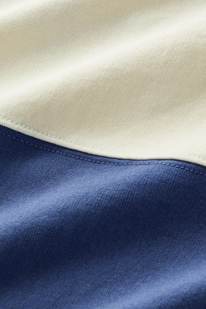 Close-up of the RM Williams Narran Heritage 3 Panel Rugby: heavyweight organic cotton jersey shows off an off-white top section and blue bottom, divided by a curved seam. The fabric’s texture and fine stitching are clearly visible.