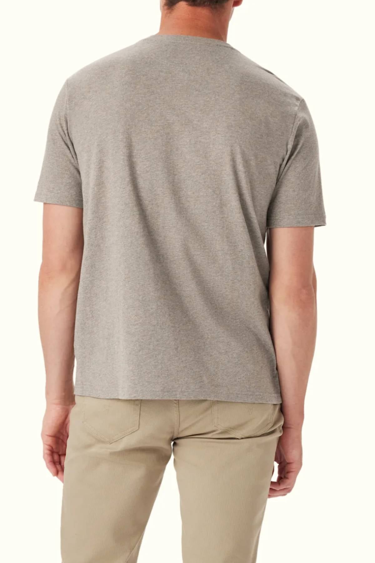 A man faces away from the camera, wearing the RM Williams Parson T-Shirt—a short-sleeve gray cotton crew neck—paired with beige pants against a plain light background.