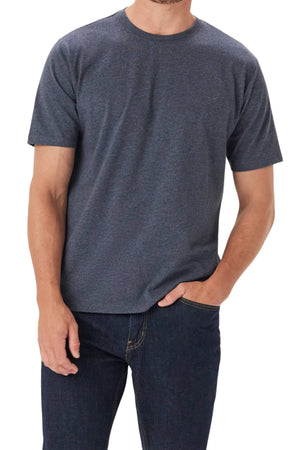 A man wearing an RM Williams Parson T-Shirt in plain dark gray and dark blue jeans stands with one hand in his pocket against a white background. His head is partially out of frame.