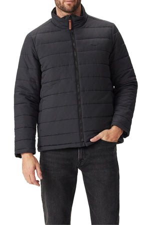 A man in the RM Williams Patterson Creek Jacket—black, quilted, recycled nylon with a stand-up collar and zip closure—paired with black jeans. Only his lower face and upper body are visible.