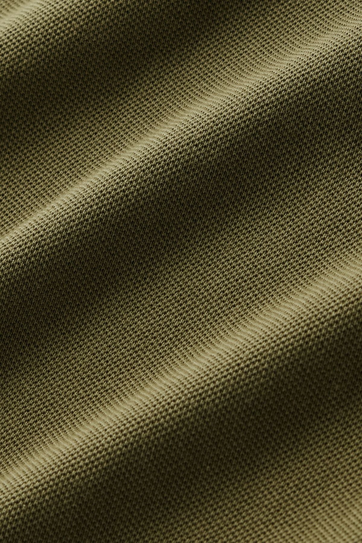 Close-up of olive green textured fabric with visible weave pattern and soft waves, highlighting the material’s texture and gentle folds—showcasing the refined craftsmanship of the RM Williams Rod Polo in premium Australian cotton and subtle Longhorn embroidery.
