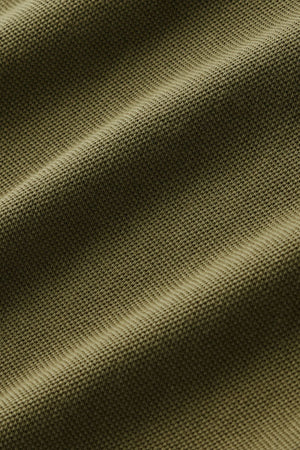 Close-up of olive green textured fabric with visible weave pattern and soft waves, highlighting the material’s texture and gentle folds—showcasing the refined craftsmanship of the RM Williams Rod Polo in premium Australian cotton and subtle Longhorn embroidery.