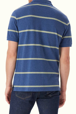 A person is shown from the back wearing the RM Williams Rod Polo—blue, short-sleeved, with light gray stripes in organic cotton—and dark jeans.