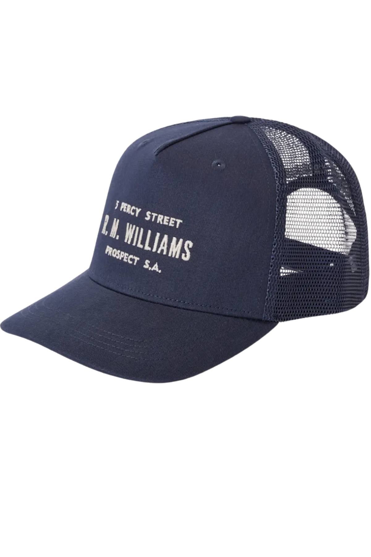 The RM Williams Stencil Trucker Cap is a navy blue organic cotton twill cap with a mesh back and white "5 Percy Street R.M. Williams Prospect S.A." text on the front.
