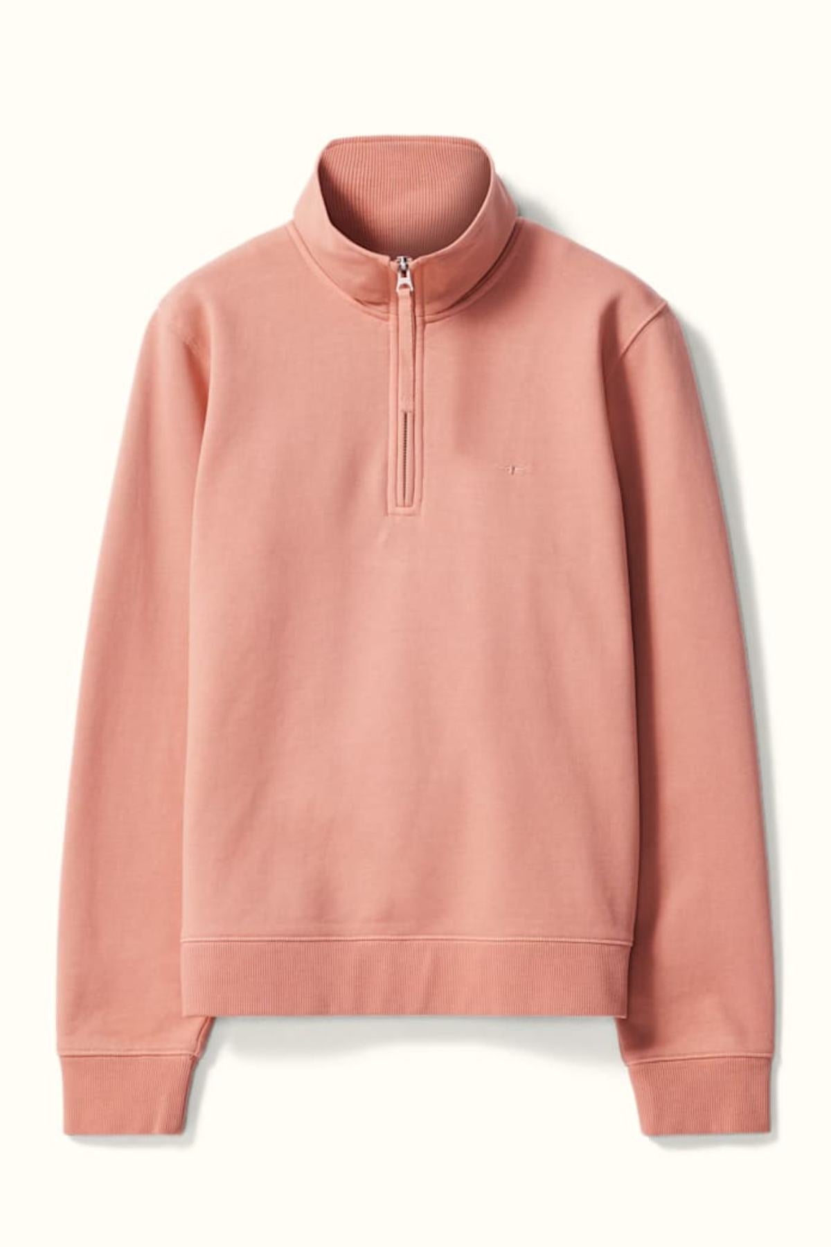 The RM Williams Trickett Zip Neck Sweatshirt is a light pink quarter-zip pullover with a stand collar, ribbed cuffs and hem, made from organic cotton. The sleek, minimal design is shown laid flat on a neutral background.