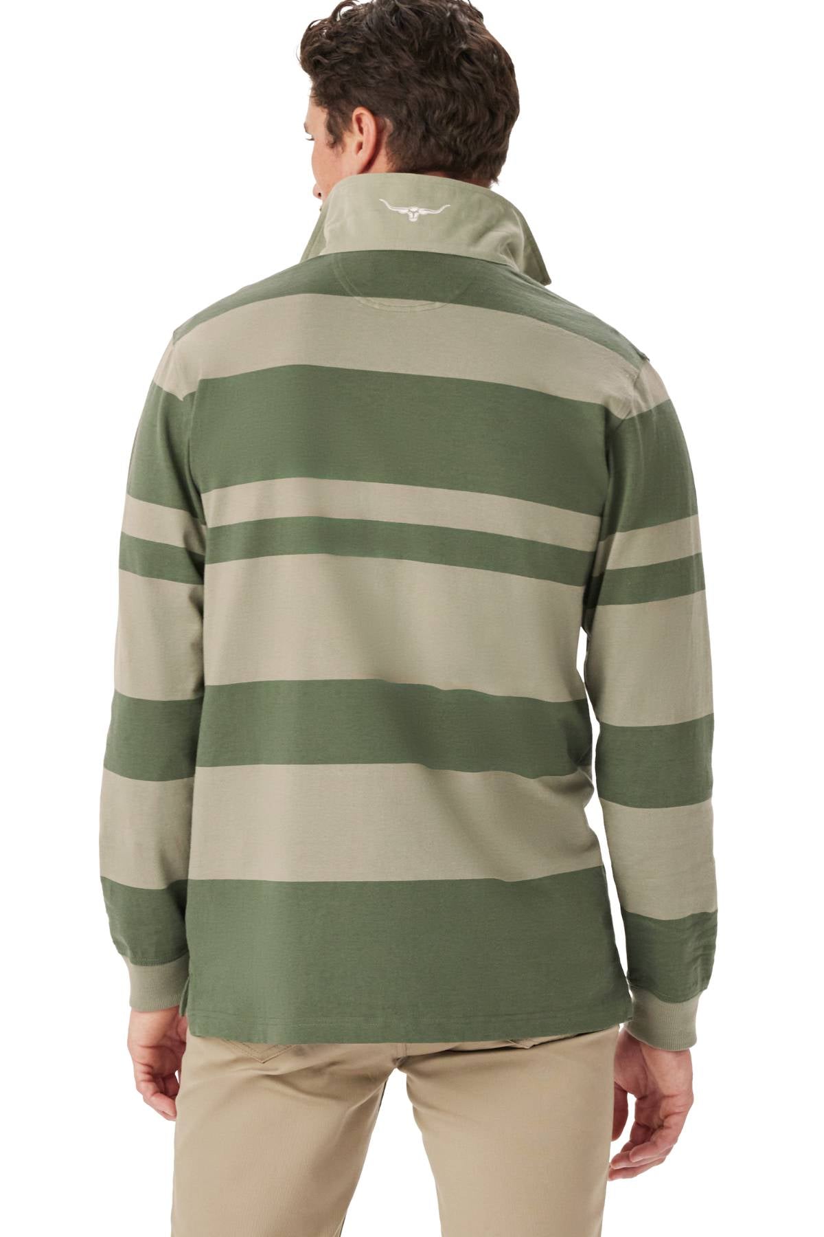 A man is seen from behind wearing the RM Williams Tweedale Rugby jersey in green and beige wide stripes, made from 100% cotton, featuring an embroidered logo at the back of the collar, paired with light pants.