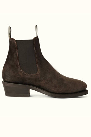 The RM Williams Comfort Lady Yearling Boot is a dark brown waxed suede Chelsea boot with a low stacked heel, black elastic side panel, pull tabs, visible stitching, and is expertly crafted in Australia. Displayed on a light background.