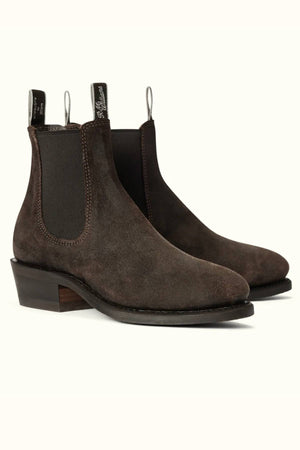 The RM Williams Comfort Lady Yearling Boot features brown waxed suede, black elastic side panels, "RM Williams" pull tabs, low stacked heels, and Goodyear welt construction, shown against a light background.