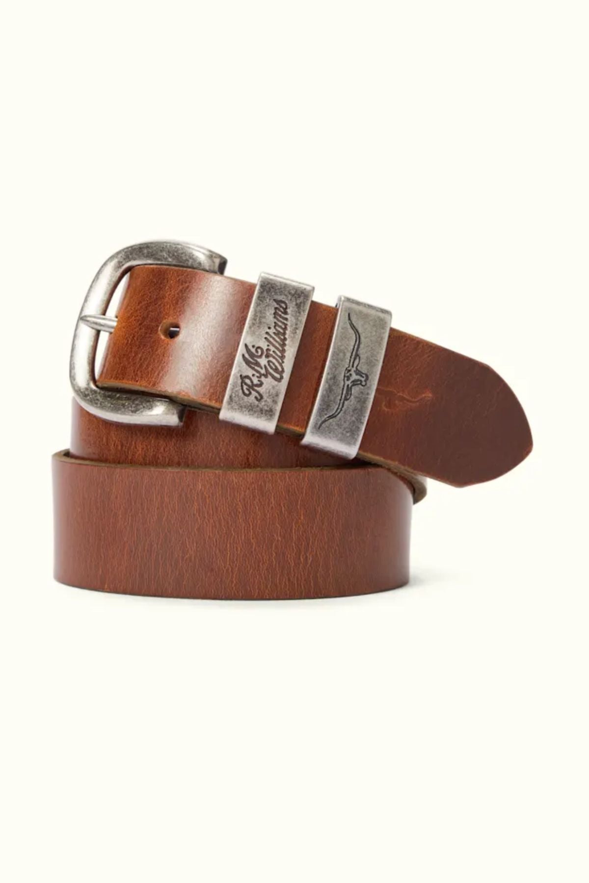 The RM Williams Drover Belt is a brown pull-up leather belt with a silver buckle, engraved text, metallic detailing, and a small winged logo on the metal loop—expertly crafted to pair perfectly with handcrafted leather boots.