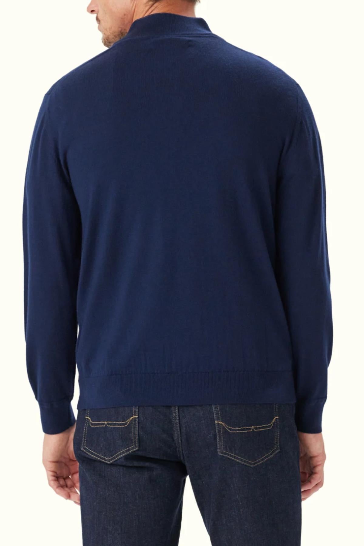 A man is seen from the back against a plain light background, wearing the RM Williams Ernest 1/4 Zip Merino Knit in navy and dark blue jeans.