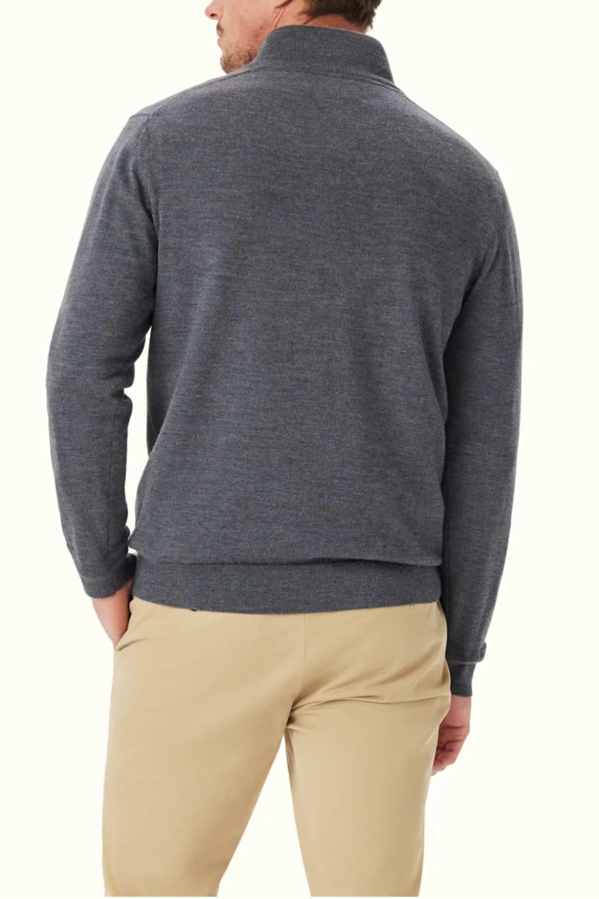 A man stands with his back to the camera, wearing the RM Williams Ernest 1/4 Zip Merino Knit sweater in gray and beige pants against an off-white background.