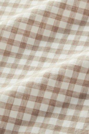 The RM Williams Johnson Check Short Sleeve Shirt features a beige and white gingham fabric with a soft texture, displaying a checkered pattern and gentle folds across the surface.