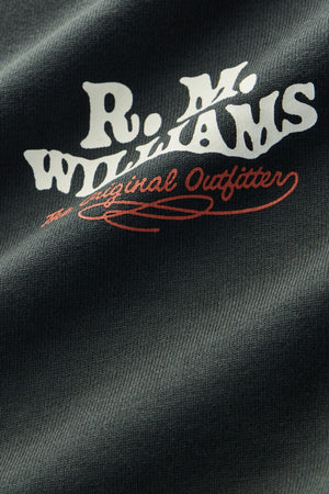 Close-up of the RM Williams Kandos Crew’s dark textured fabric, featuring “R.M. WILLIAMS” in bold white lettering and “The Original Outfitter” in red cursive text.