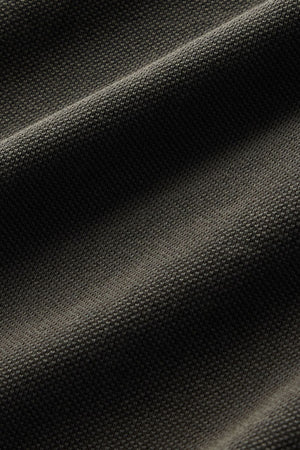 Close-up of the RM Williams Rod Polo in dark gray, featuring textured fabric with diagonal waves and a subtle grid-like pattern, highlighting the fine weave detail and shadowing from the folds.