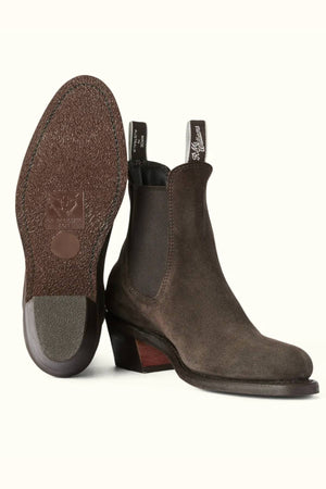 A pair of brown suede leather RM Williams Rosebery Boots; one stands upright for a side view, the other tilted to show the textured sole and tapered block heel. Both boots feature branded pull tabs.