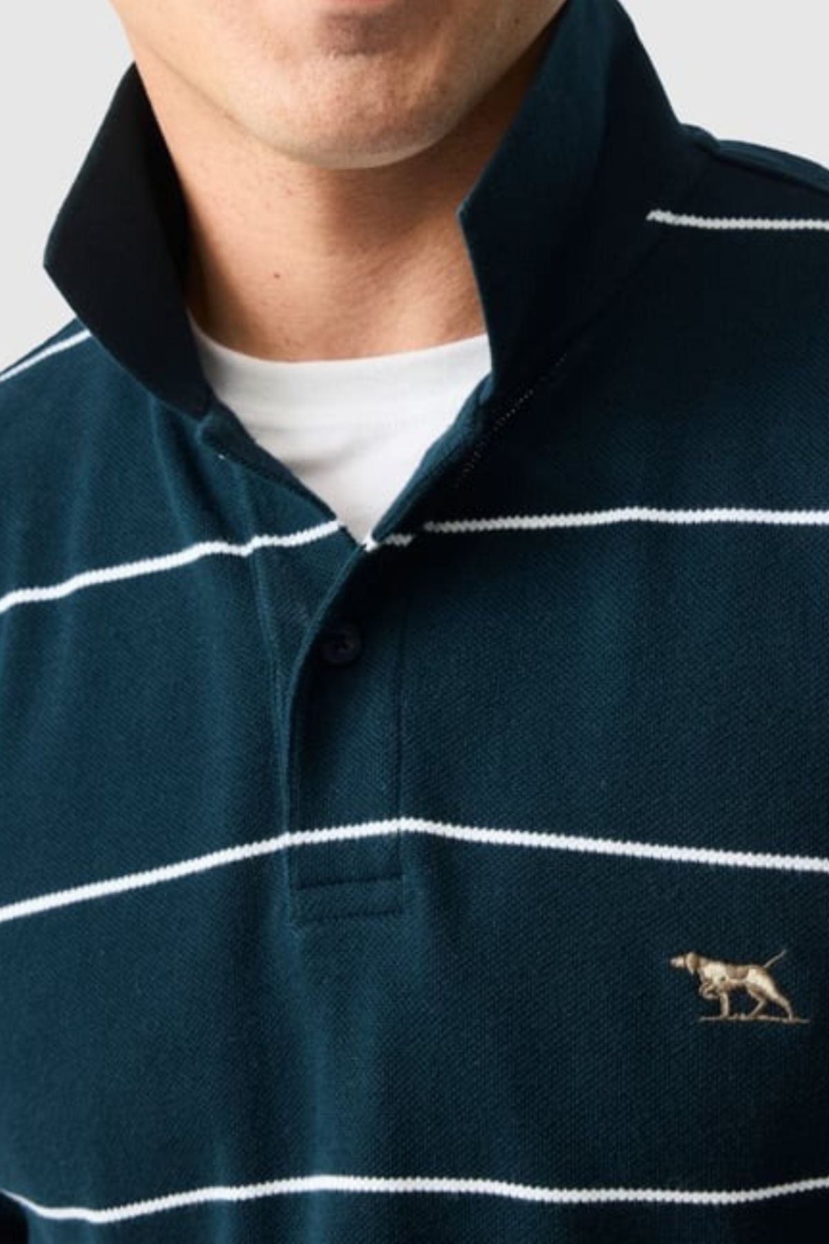 Someone wearing a dark green Rodd & Gunn Glen Eden Polo over a white T-shirt, with horizontal white stripes, an embroidered dog logo on the chest, and a slightly raised high-retention rib collar for extra style.