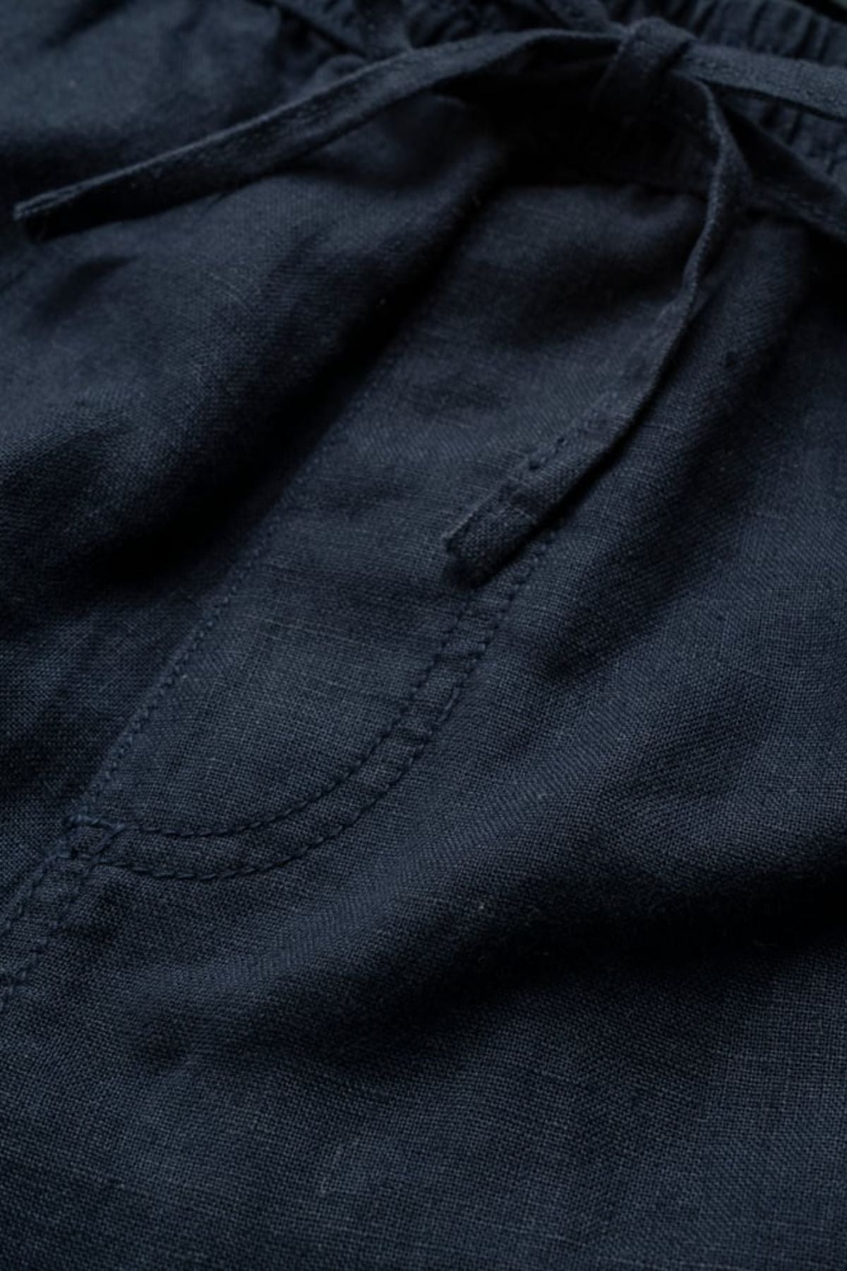 Close-up of Rodd & Gunn Linen Resort Short in dark navy blue, featuring a front pocket, visible stitching, and a drawstring waistband tied in a bow.