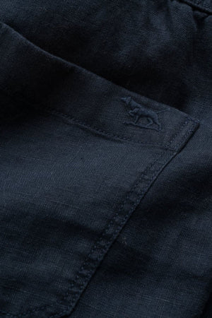 Close-up of a dark blue pocket on the Rodd & Gunn Linen Resort Short, featuring subtle stitching and an embroidered rhinoceros logo near the pocket opening.