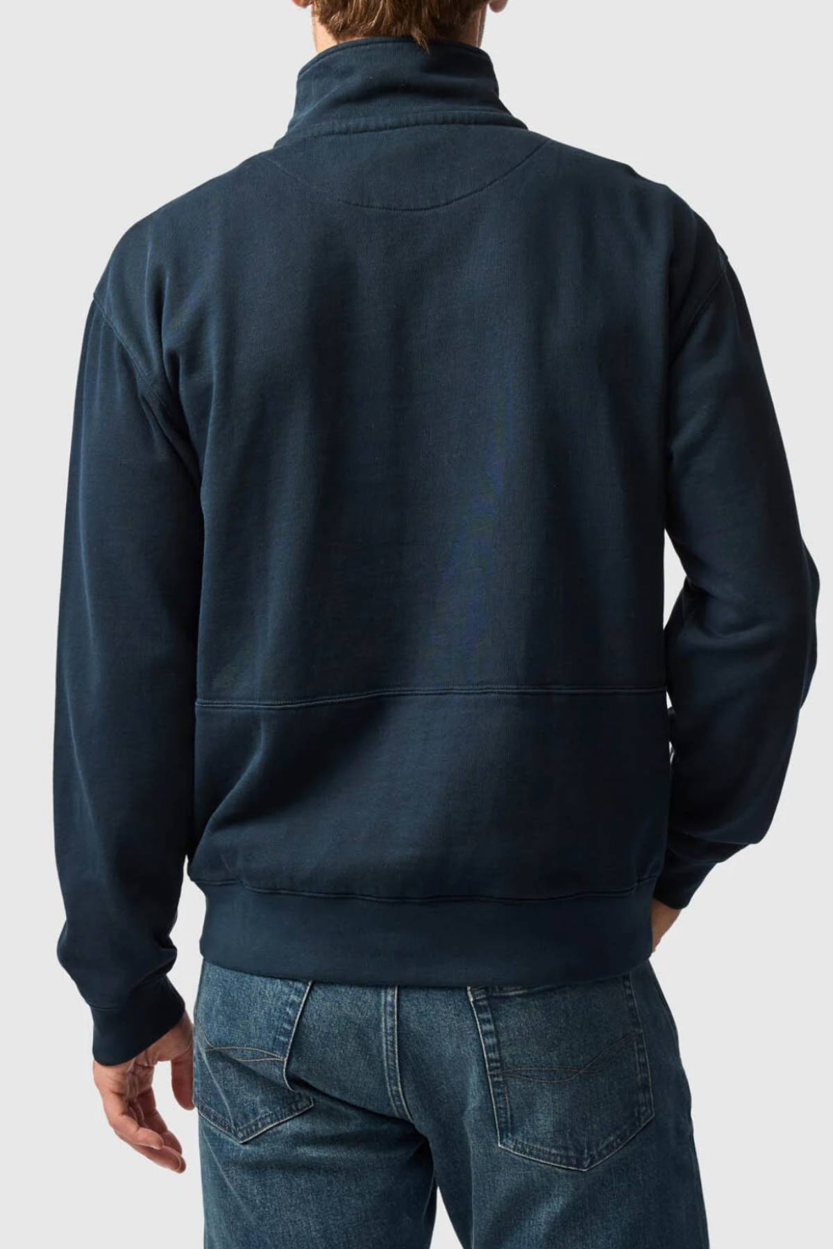 A person wearing a dark blue Rodd & Gunn Milford Sound Sweat with a YKK metal zip and blue jeans, shown from the back against a plain light gray background.