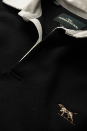 Close-up of the Rodd & Gunn Otago Sweat, a black polo shirt with a classic twill rugby collar and a small signature pointer logo embroidered on the chest.