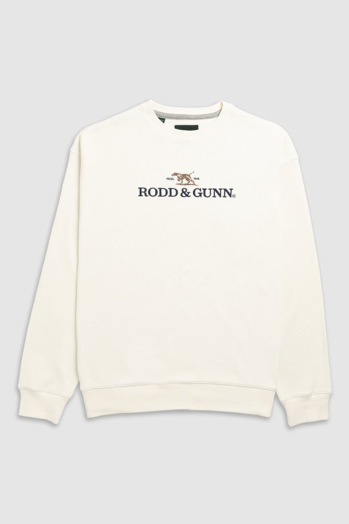 The Rodd & Gunn Bromley Sweat is a cream crewneck with a front logo and embroidered dog, made from recycled polyester, shown on a plain gray background.