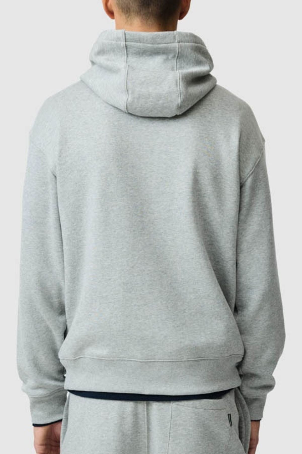 A person is seen from the back against a plain background, wearing the Rodd & Gunn Otago Hoodie in light gray along with matching sweatpants, both crafted from soft, brushed back fleece.