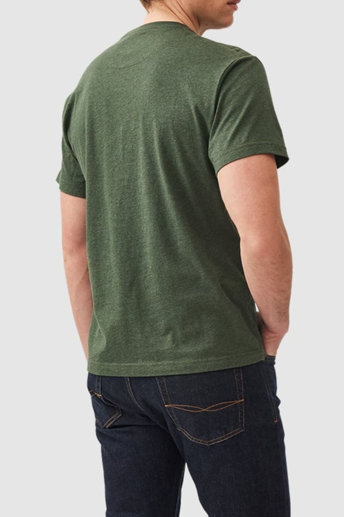 Wearing a sports fit green Rodd & Gunn The Gunn T-Shirt made from Australian cotton and dark blue jeans, a person stands with their back to the camera against a plain background.