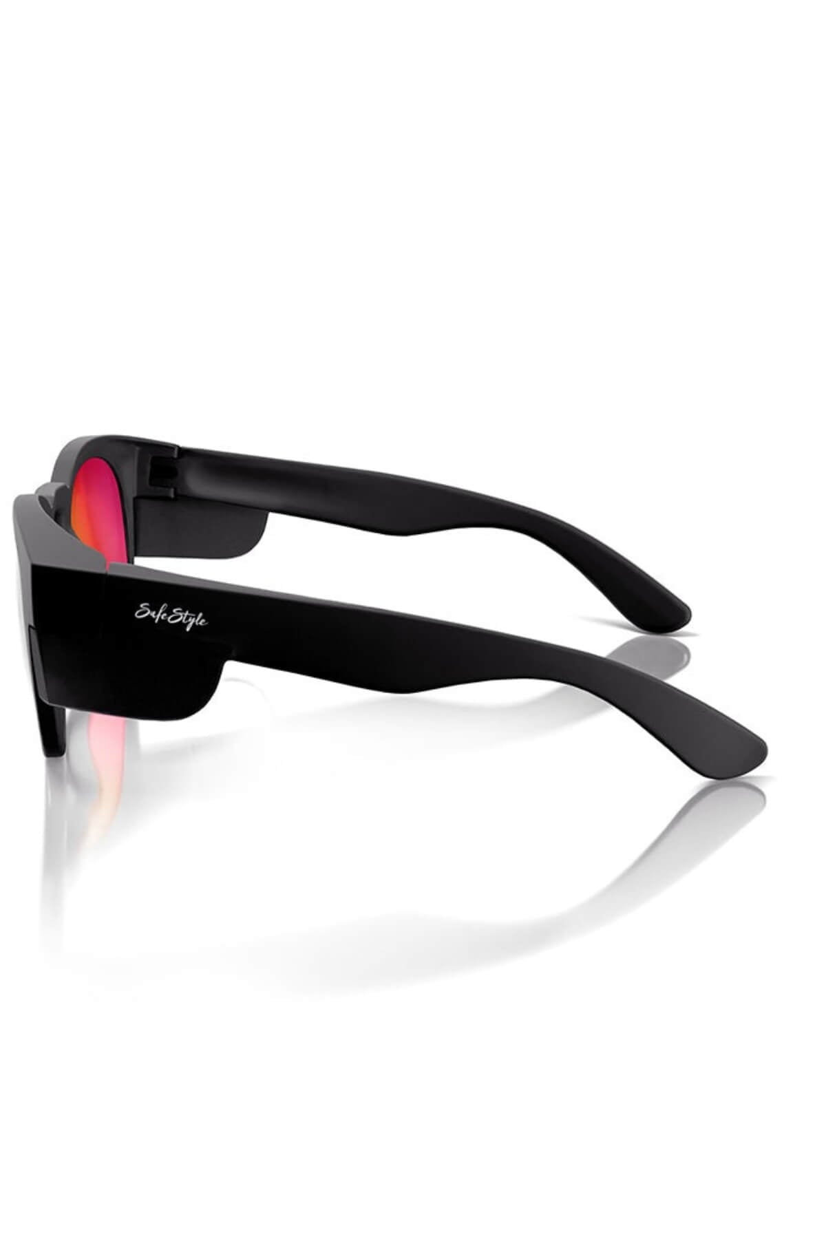 SafeStyle Cruisers Sunglasses feature matte black frames and mirror red polarized lenses in a side view. The temple arm displays a small white logo, providing UV protection, with their stylish design casting a reflection on the white surface below.