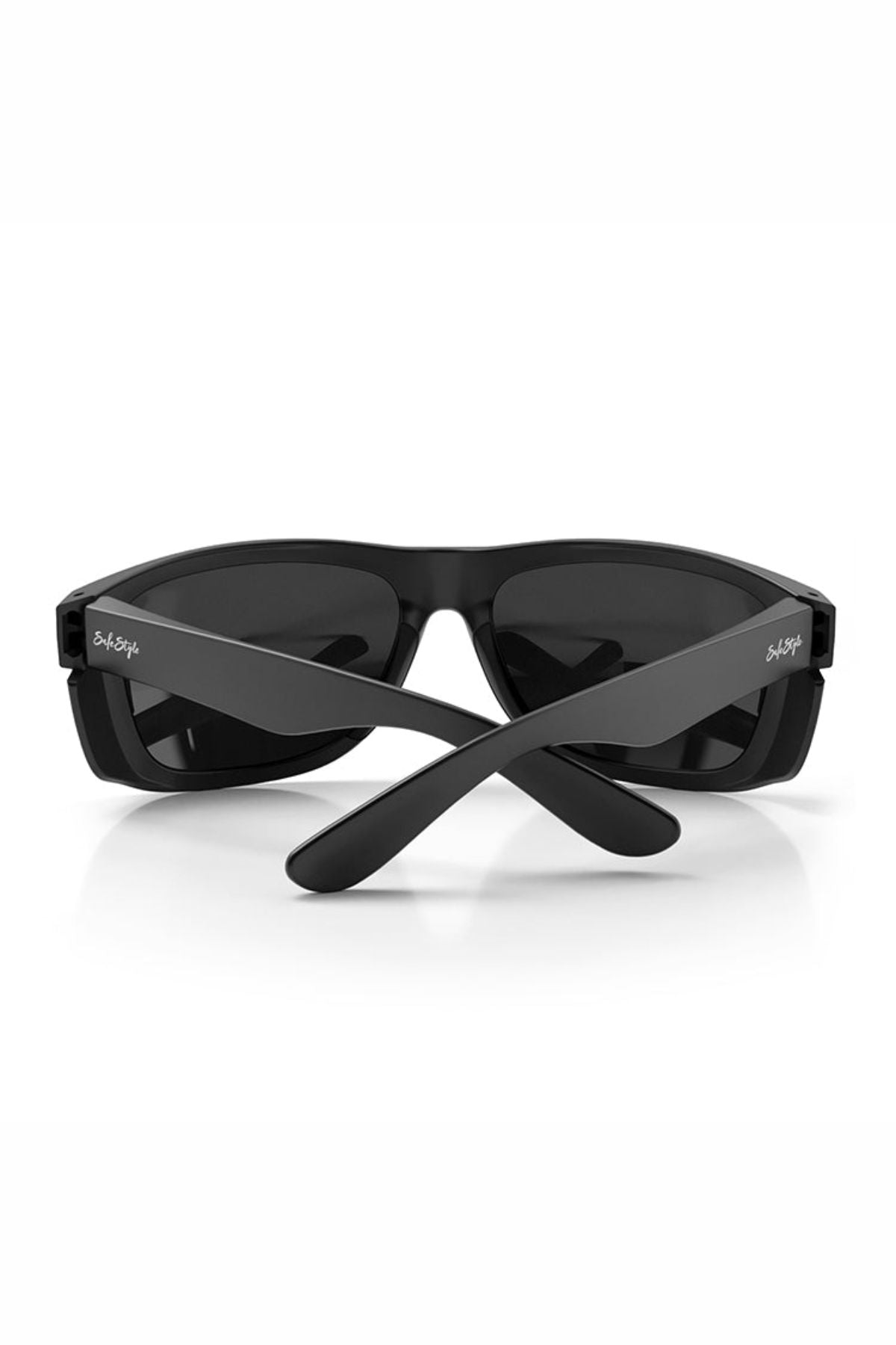 The SafeStyle Rapids Matte Black Frame Polarised Lens sunglasses are shown from the back with crossed arms. The brand logo is visible near the hinges, highlighting these shatterproof sunglasses with reliable UV protection.