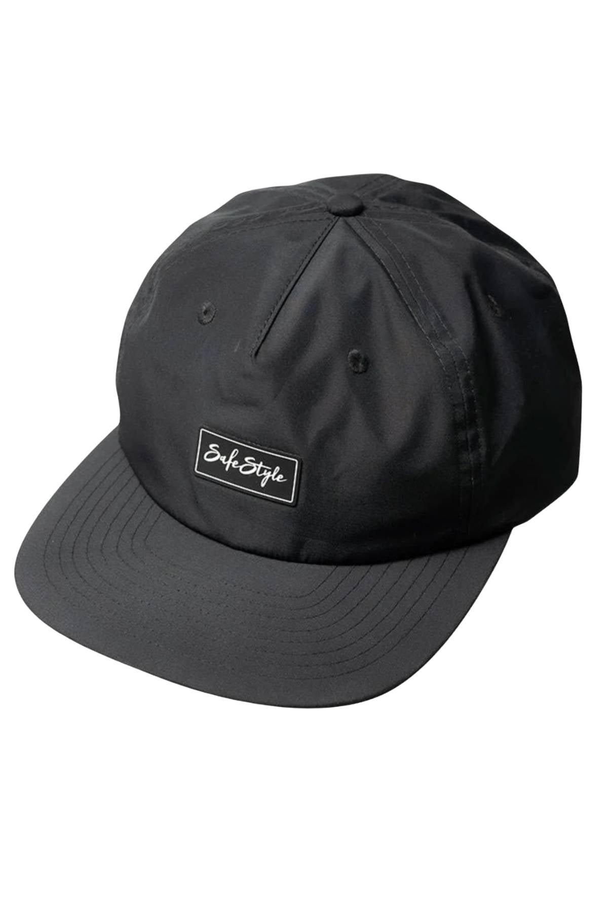 The Safestyle Worksite to Weekend Essentials Cap is a black flat-brim cap made from recycled polyester, featuring a rectangular "Safe Style" patch, stitched eyelets for ventilation, and UPF 50+ for all-day sun protection.