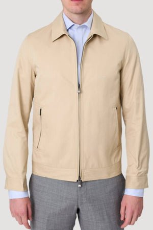 A man wears the Savile Row James Zip Front Jacket, made from 100% cotton, over a light blue dress shirt and gray trousers. He stands against a plain light gray background with his head partially out of frame.